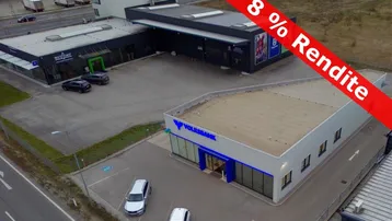 Luftaufnahme eines Gewerbekomplexes mit mehreren Gebäuden und Parkplätzen, inklusive einer Bankfiliale.