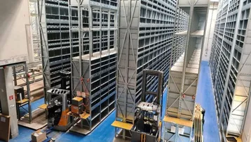 Große Lagerhalle mit hohen Regalsystemen und Gabelstaplern für effiziente Logistikabläufe.