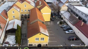Luftaufnahme eines Gebäudekomplexes mit gelben Fassaden, roten Dächern und einem Parkplatz im Winter.