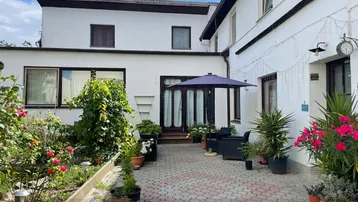 Gepflasterter Innenhof mit Gartenmöbeln, Sonnenschirm und blühenden Pflanzen.