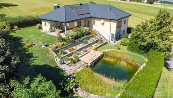 Luftaufnahme des Hauses mit großem Garten, Teich und Photovoltaikanlage in ländlicher Umgebung.