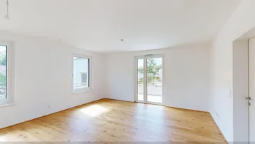 Helles, leeres Zimmer mit Parkettboden und Zugang zu einem Balkon, ideal als Wohnbereich.