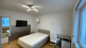 Helles Schlafzimmer mit Holzboden, Schreibtisch und Wandfernseher, gut gepflegt.