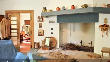 Wohnzimmer mit großem, offenem Kamin und Durchgang zu einem weiteren Raum.
