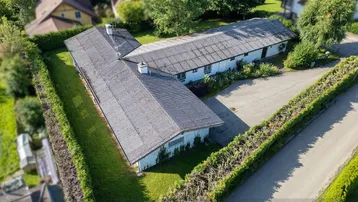 Luftaufnahme des L-förmigen Gebäudes mit gepflegter Hecke und grüner Umgebung.