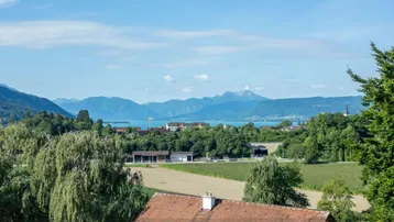 Weitläufiger Panoramablick auf einen See und die umliegende Berglandschaft.