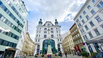 Historisches Gebäude an einer belebten Straße in der Stadt mit moderner Architektur im Hintergrund.