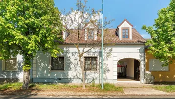 Vorderansicht eines traditionellen Hauses mit Gaubenfenstern und einem überdachten Eingangsbereich.