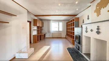 Geräumiger Wohnbereich mit Kaminofen, Einbauregalen und hellem Holzfußboden.