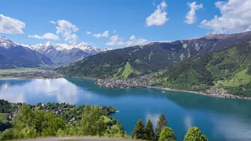 Panoramablick auf einen malerischen See, umgeben von schneebedeckten Bergen und einer charmanten Stadt.