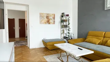 Helles Wohnzimmer mit gelbem Sofa, modernem Couchtisch und Blick in den Flur mit Parkettboden.