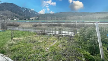 Großer Gartenbereich mit Rasenfläche und Blick auf die umliegenden Berge.