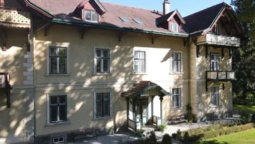 Historische Villa mit klassischer Architektur, mehreren Fenstern und einem gepflegten Vorgarten.