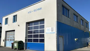 Gewerbegebäude mit großen Rolltoren und blauer Wellblechfassade, ideal für KFZ-Technik.