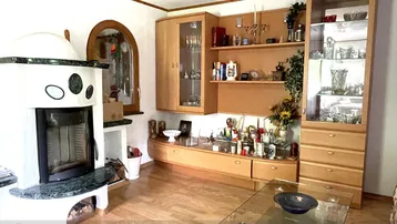 Wohnzimmer mit traditionellem Kachelofen, Holzmöbeln und einem Bogenfenster.