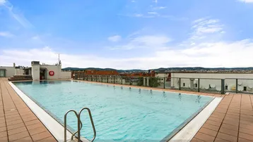 Großzügiger Dachpool mit weitem Blick über die Stadt und umliegende Gebäude.