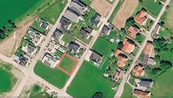 Luftaufnahme eines Wohngebiets mit einem markierten Baugrundstück in grüner Umgebung.