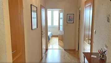 Langer Flur mit Holztüren und einem Blick in ein helles Schlafzimmer am Ende.