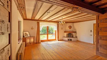 Geräumiges Wohnzimmer mit kunstvoll geschnitzter Holzdecke, Kamin und Holzboden, hell und einladend.