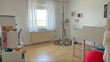Kinderzimmer mit Laminatboden, Einzelbett und Blick ins Grüne durch das Fenster.