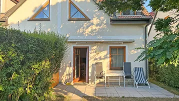 Gemütliche Terrasse mit Gartenmöbeln vor dem Haus und grüner Hecke.