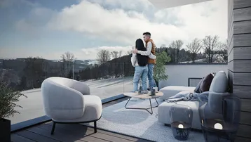 Gemütlicher Balkon mit moderner Bestuhlung, Glasgeländer und weitem Blick über eine verschneite Landschaft.