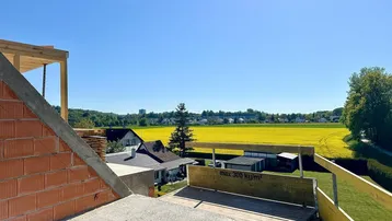 Blick von der Baustelle auf die umliegende Landschaft mit gelben Feldern und Häusern.