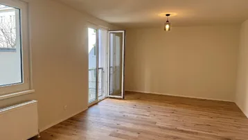Heller Wohnraum mit neuem Parkettboden und Zugang zu einem französischen Balkon.