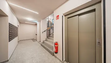 Heller Eingangsbereich mit Briefkästen, Treppenhaus und modernem Aufzug.
