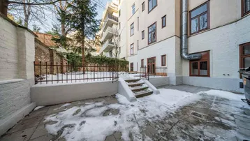 Verschneiter Innenhof mit gepflastertem Bereich, Bäumen und einer umgebenden Mauer.