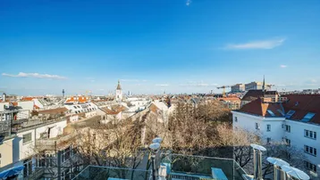 Panoramablick über die Dächer der Stadt Wien mit historischer Architektur und blauem Himmel.