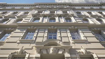 Detailansicht der historischen Fassade mit aufwendigen Stuckelementen und großen Fenstern.