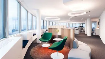 Modernes Büro mit großen Fenstern, grünen Sesseln und einem runden Teppich als gemütliche Lounge-Ecke.