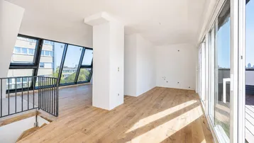 Lichtdurchfluteter, offener Wohnbereich mit modernem Holzboden, großen Schrägfenstern und direktem Zugang zur Dachterrasse.