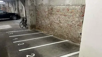 Tiefgaragenstellplatz mit nummerierter Markierung und unverputzter Ziegelwand im Hintergrund.