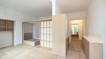 Helles Studio-Apartment mit modernem Design, Fischgrätparkett und integriertem Schlafbereich hinter Schiebetüren.