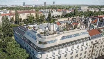 Luftaufnahme eines modernen Gebäudes mit Dachausbau und Stadtblick bei Tageslicht.