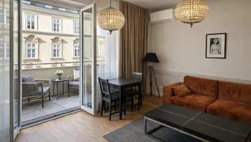 Heller Wohn- und Essbereich mit Holzboden, gemütlichem Sofa und Zugang zu einem Balkon.