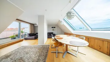Heller Wohn- und Essbereich mit Holzboden, Dachfenstern und Zugang zur Terrasse.