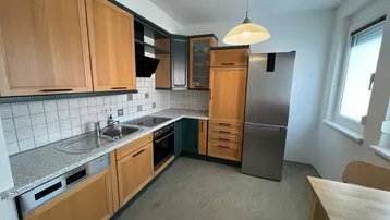 Funktionale Küche mit Holzfronten, modernen Geräten und einem Fenster für Tageslicht.