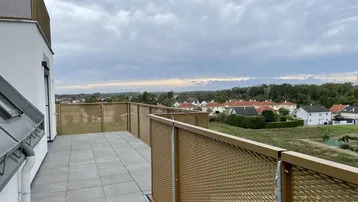 Geräumige Dachterrasse mit modernen Fliesen und Blick auf die umliegende Wohngegend und Natur.