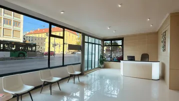 Moderne Empfangshalle mit großen Fenstern zur Straße und hellem Fliesenboden, ideal für ein Büro.