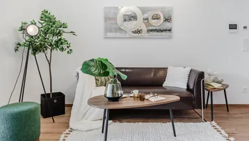 Helles Wohnzimmer mit modernem braunem Sofa, Holzboden und stilvoller Dekoration.