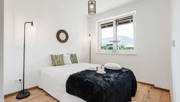 Gemütliches Schlafzimmer mit Holzboden, großem Fenster und Blick auf die grüne Umgebung.