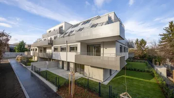 Modernes Mehrfamilienhaus mit mehreren Balkonen und privaten Gartenbereichen im Erdgeschoss.