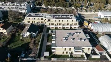 Luftaufnahme der modernen Wohnanlage mit Flachdächern, Solaranlagen und umliegender Bebauung.