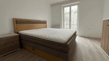Schlafzimmer mit Doppelbett, Nachttischen und Zugang zu einem französischen Balkon.