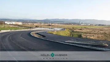 Neue Straße und Kreisverkehr in einem Entwicklungsgebiet mit weitem Blick auf die Landschaft und Berge.