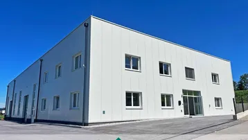 Modernes Geschäftsgebäude mit klarer Architektur und großen Fenstern unter blauem Himmel.