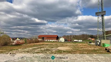 Weitläufiges Gewerbegrundstück unter bewölktem Himmel mit umliegenden Gebäuden und einem Sendemast.
